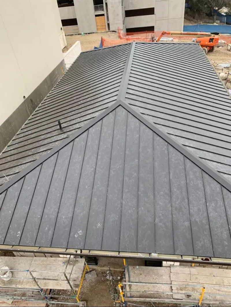 Commercial metal roof construction with crane equipment in Economy